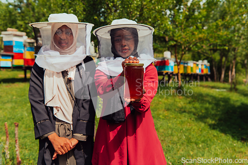 Image of Portrait of a Arab investitors in the beekeeping department of a honey farm holding a jar of honey in her hand