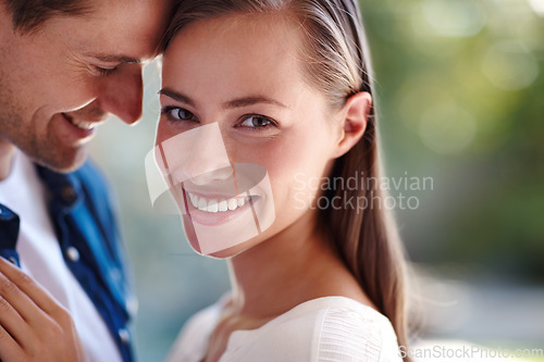 Image of She means the world to him. A young man holding his girlfriend while standing outdoors on a sunny day.