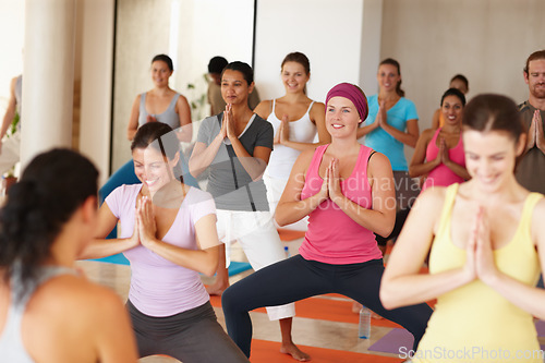 Image of Enjoying their yoga workout. Shot of a group of smiling yoga students standing in front of their teacher and following her movements.