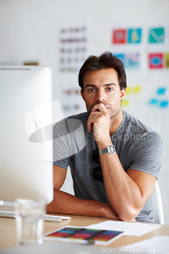 Image of Thinking creative thoughts. A handsome young man sitting in front of his computer looking pensive.