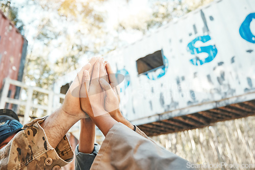 Image of Paintball, hands and high five for support, motivation or teamwork in game plan, collaboration or unity on battlefield. Group of people touching hand in goal, team or trust together for match start