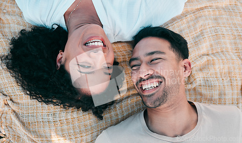 Image of Face, picnic and smile with a couple laughing on a blanket from above, lying on the ground while on a date. Love, happy or funny with a man and woman bonding together for romance on valentines day