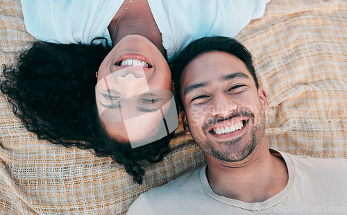 Image of Portrait, picnic and smile with a couple on a blanket from above, lying down on the ground while on a date. Face, love or happy with a man and woman bonding together for romance on valentines day
