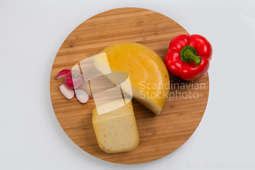 Image of Bosnian traditional cheese served on a wooden container with peppers, parade and onions isolated on a white background