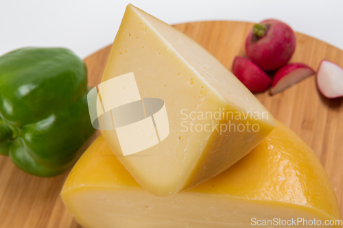 Image of Bosnian traditional cheese served on a wooden container with peppers, parade and onions isolated on a white background