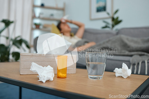 Image of Pills, tissue and glass on table, living room or sick woman laying on sofa with stress, pain or frustrated. Girl, allergies or medical problem with water, medicine or fatigue on lounge couch in home