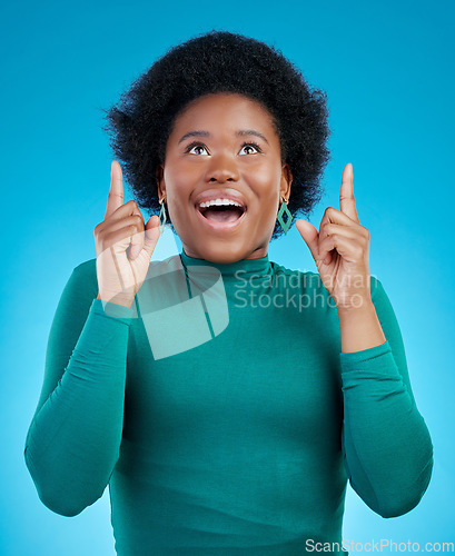 Image of Hands, pointing up and black woman with wow news in studio for promo, announcement or deal on blue background. Omg, surprise and African female model show sale, coming soon or how to sign up steps