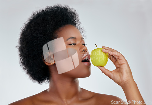 Image of Black woman, hair and apple for natural nutrition, diet or vitamins against a white background in studio. Face of African female person eating organic fruit for healthy wellness, fiber or body care