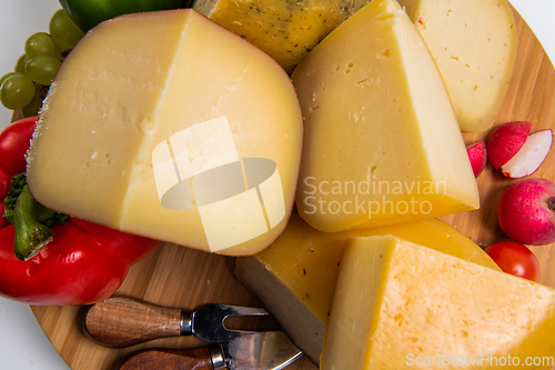 Image of Bosnian traditional cheese served on a wooden container with peppers, parade and onions isolated on a white background