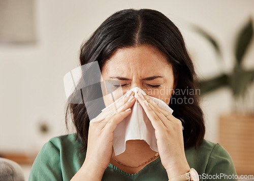 Image of Blowing nose, tissue and woman in a living room with flu, cold and hay fever, crisis or viral infection in her home. Sneezing, allergies and person with virus or coughing illness in a lounge in house