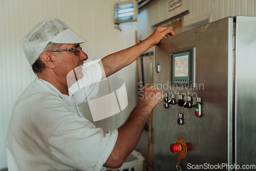 Image of Cheese maker working in the modern industry on machines that are using for the machining of fresh cheese