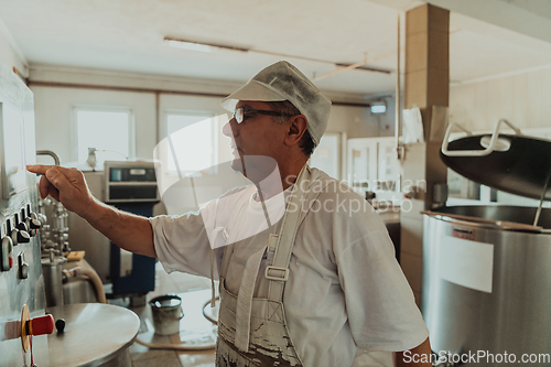 Image of Cheese maker working in the modern industry on machines that are using for the machining of fresh cheese