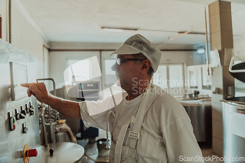 Image of Cheese maker working in the modern industry on machines that are using for the machining of fresh cheese