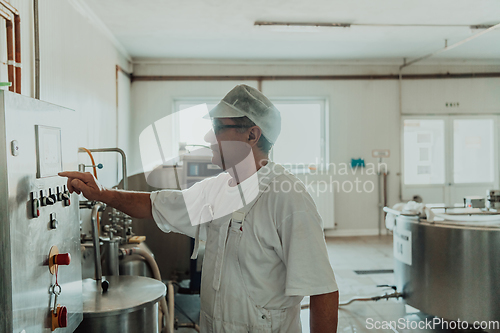 Image of Cheese maker working in the modern industry on machines that are using for the machining of fresh cheese