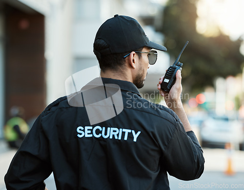 Image of Radio, man and a security guard or safety officer outdoor on a city road for communication. Back of a person with a walkie talkie on urban street to report crime for investigation and surveillance