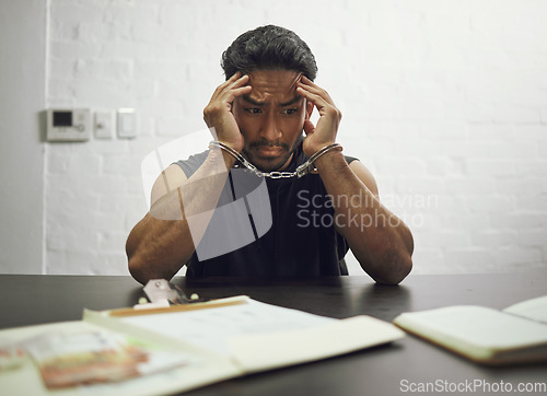 Image of Man, criminal and handcuffs in fear for interrogation, drugs or crime in arrest on table in room. Worried male person, gangster or suspect in jail, justice or guilty fraud, theft or illegal substance