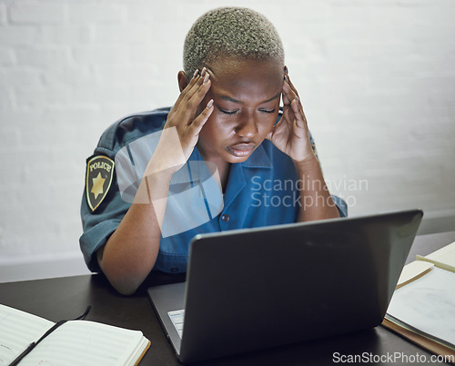 Image of Police, woman with headache and working with stress on computer or frustrated with case, report or anxiety in security. African, officer and tired from work on documents in office or station