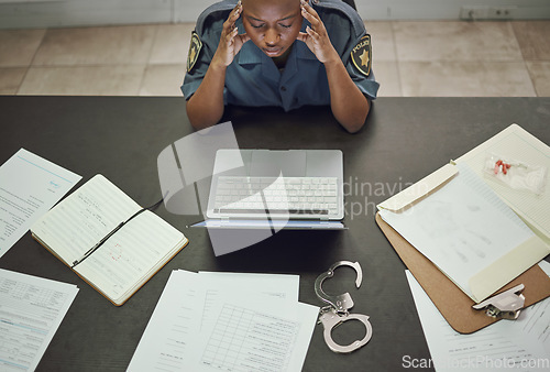 Image of Police, woman and working with stress at desk with documents, paperwork or frustrated with headache from working on computer case, report. Security, officer and tired from work in office or station