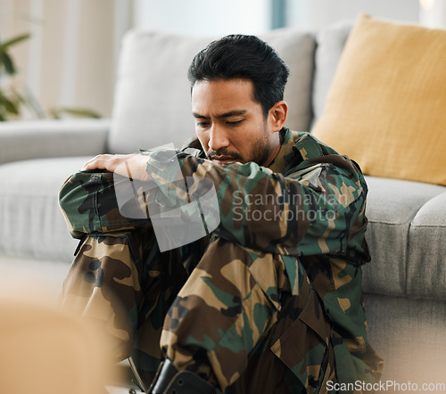 Image of Sad, trauma and male military soldier sitting on the floor in the living room of his house. Depression, ptsd and man army warrior from Mexico thinking about mental health in the lounge at home.