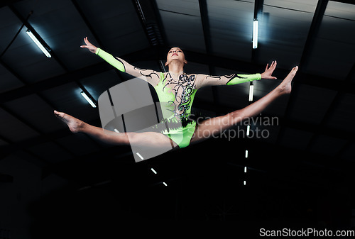 Image of Woman, jump and gymnastics with fitness and competition, action and body with performance in arena. Female gymnast in air, athlete exercise with flexibility and health for sports, flying and acrobat