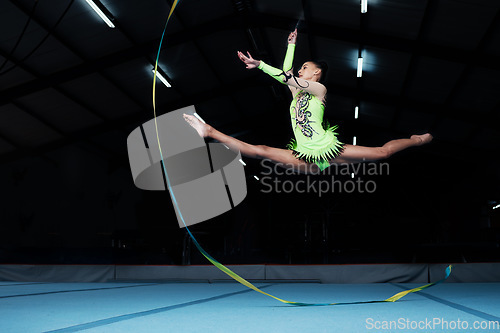 Image of Jump, rhythmic gymnastics and woman in gym with ribbon, creative sport or action, performance or fitness. Competition, athlete and female gymnast, dance and art with body, routine and energy at arena