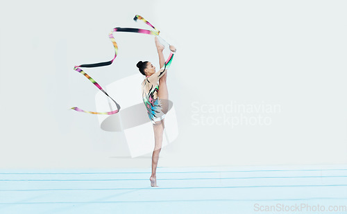 Image of Gymnastics performance, woman and ribbon with legs split for competition, sport and show on studio floor. Gymnast, athlete girl or professional dancer for balance, training or contest for creativity