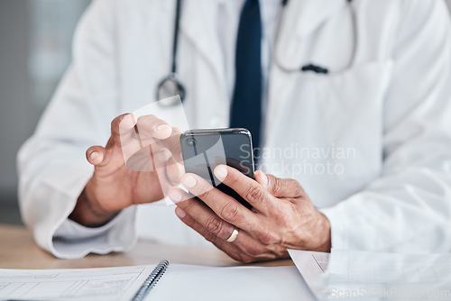 Image of Smartphone, hands and doctor typing at table in hospital for research, telehealth or healthcare. Phone, medical professional or surgeon, expert or person on wellness app, email or online consultation