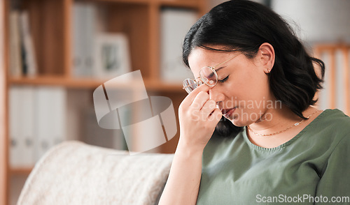 Image of Migraine, stress and young woman in her living room with a burnout or mental health problem. Headache, tired and exhausted female person sitting on a sofa in the living room of her modern apartment.