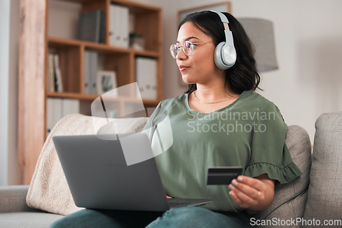 Image of Woman, laptop and credit card with headphones and online shopping on sofa, music subscription payment and fintech. Female customer at home, thinking of finance with e commerce and podcast membership