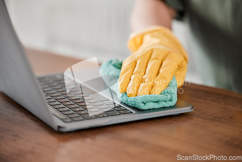 Image of Person, hands and cleaning laptop for disinfection, bacteria or germ removal on wooden table at home. Closeup of housekeeper, cleaner or maid wiping computer in sanitizing, hygiene or clean equipment