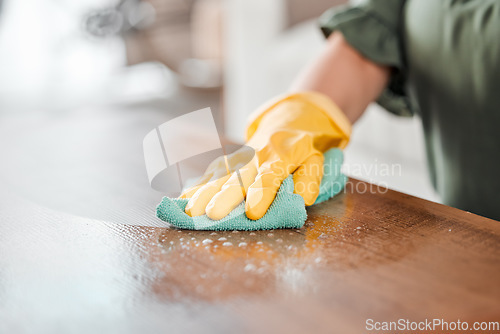 Image of Hands, cleaning and bacteria on a wooden table for hygiene, disinfection or to sanitize a surface in a home. Gloves, spray and product with a woman cleaner in the living room for housework or chores