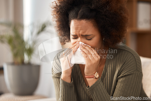 Image of Sick woman, blowing nose and tissue with flu, illness or infection disease in living room at home. Sad, frustrated or ill female person with allergy, sinus or fever sneezing in living room at house