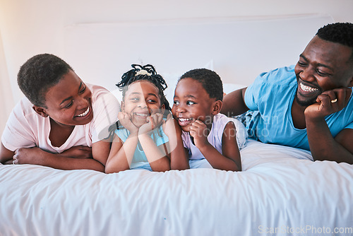 Image of Smile, bond and black family in bed happy, talking and relax in their home on weekend. Love, face and children with parents in bedroom playful, free and chilling while enjoying conversation together