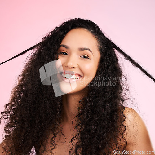 Image of Face, woman and curly hair pull for beauty in studio isolated on a pink background. Portrait, natural cosmetics and hairstyle of happy model in salon treatment for growth, wellness and aesthetic