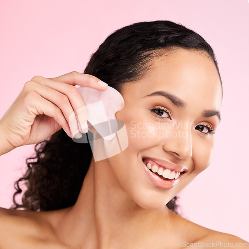 Image of Gua sha, face massage and woman with natural beauty, skin glow and cosmetics. Portrait of a young aesthetic female model happy with self care, facial or dermatology results on a pink background