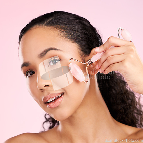 Image of Face roller, natural beauty and woman with skin glow, health or wellness cosmetics. Headshot of a young aesthetic female model with dermatology and facial massage results on a pink background