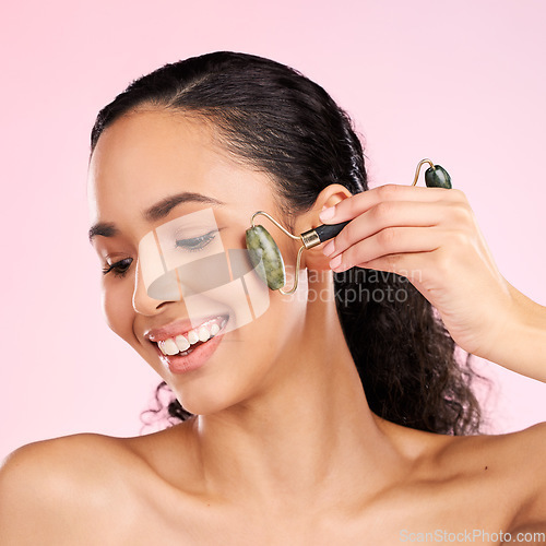 Image of Natural beauty, facial roller and woman with skin glow, health or wellness cosmetics. Face of a young aesthetic female model happy with dermatology or skincare massage results on a pink background