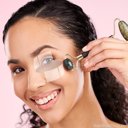 Image of Facial roller, natural beauty and woman with skin glow, health or wellness cosmetics. Portrait of a young aesthetic female model happy with dermatology or stone massage results on a pink background