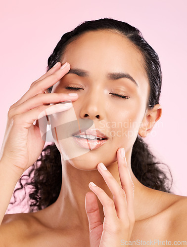 Image of Skin, beauty and hands on face of a woman in studio for cosmetics, dermatology and glow. Headshot, moisturizer and touch for natural skincare of a young female aesthetic model on a pink background