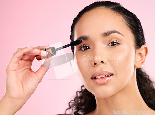 Image of Beauty, mascara and makeup on face of a woman in studio for eyelash cosmetics and skin glow. Portrait, application and skincare tools or product of a young female aesthetic model on a pink background