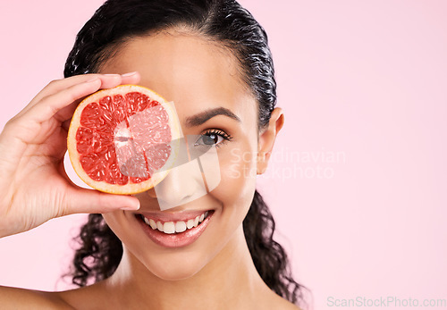 Image of Face, skincare and happy woman with grapefruit in studio isolated on a pink background mockup space. Portrait, natural cosmetic or model with fruit, food or nutrition, healthy vegan diet or vitamin c