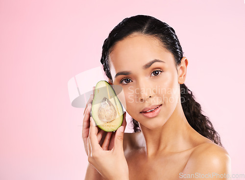 Image of Face, skincare and serious woman with avocado in studio isolated on pink background mockup space. Portrait, natural cosmetic and model with fruit, food or nutrition for diet, vegan health or omega 3