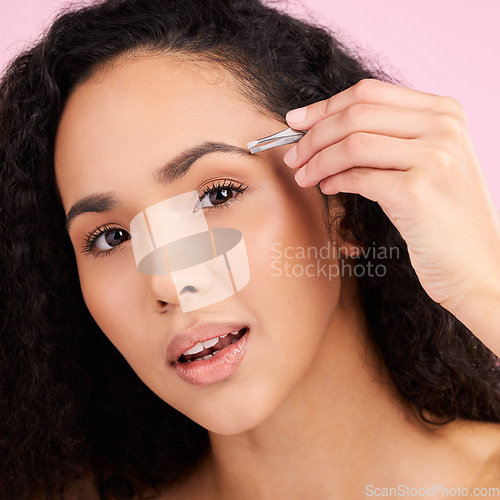 Image of Face, beauty and woman with tweezer for eyebrow in studio isolated on pink background. Natural portrait, facial plucking or hair removal of serious model for self care, wellness or grooming aesthetic