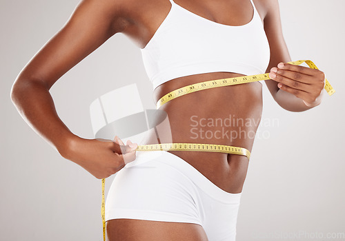 Image of Tape measure, diet and stomach or body of woman for health and wellness on studio background. Fitness, progress or underwear and waist of aesthetic female model for weight loss, balance or motivation