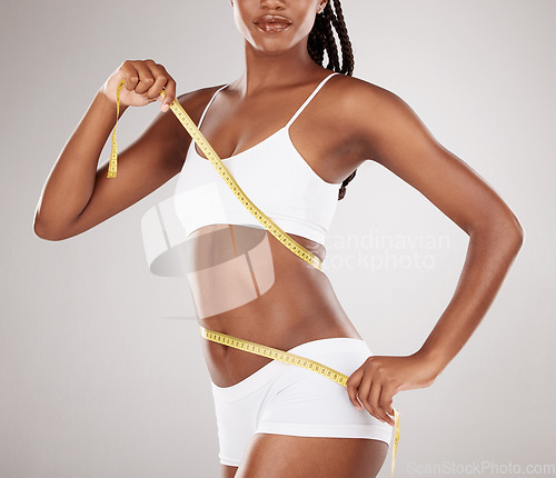 Image of Diet, tape measure and stomach or body of woman for health and wellness on studio background. Fitness, progress or underwear and waist of aesthetic female model for weight loss, tummy tuck or lipo