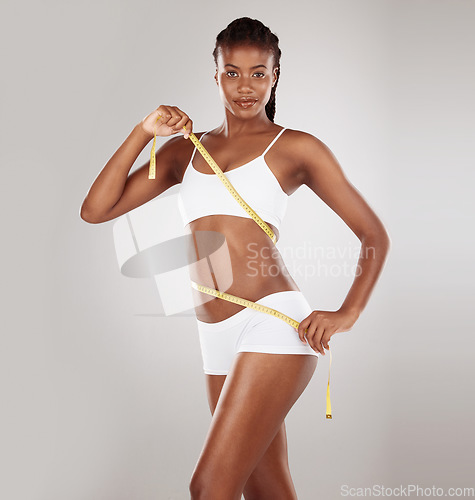 Image of Tape measure, diet and stomach or body of woman for health and wellness portrait on studio background. Fitness, progress or underwear and waist of black female model for weight loss, balance or goals