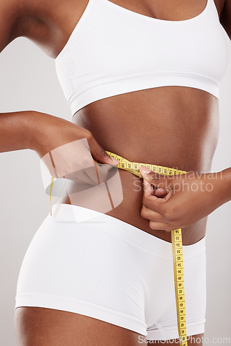 Image of Tape measure, waist and stomach or body of woman for health and wellness on white background in studio. Fitness, progress and underwear of model on diet for weight loss goals, balance or motivation