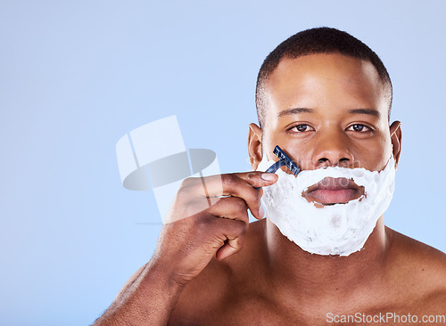 Image of Beard hair removal, cream and portrait of a black man on a blue background for grooming and beauty. Serious, spa and face of an African person with a razor for shaving and cleaning on the face