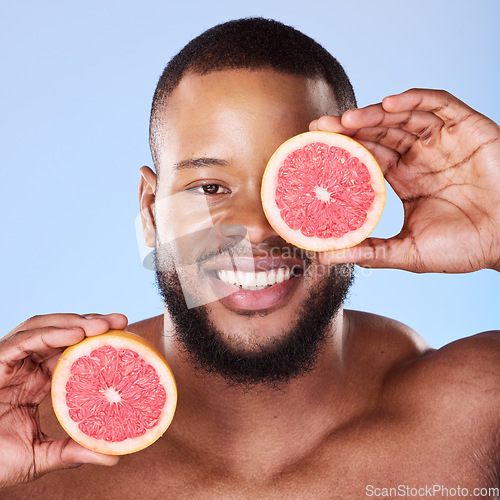 Image of Black man, grapefruit and studio portrait for skincare, detox or vitamin c for smile, health or wellness by background. African guy, model and citrus fruit in hands by eye, facial beauty or nutrition