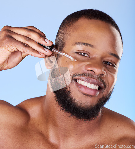 Image of Black man, portrait and serum for face in studio, aesthetic skincare or dermatology on blue background. Happy male model, facial cosmetics and dropper of hyaluronic acid, collagen and oil for beauty